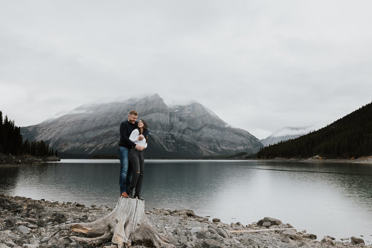 couple standing on a log in Kananaskis Country for their Engagement Photos