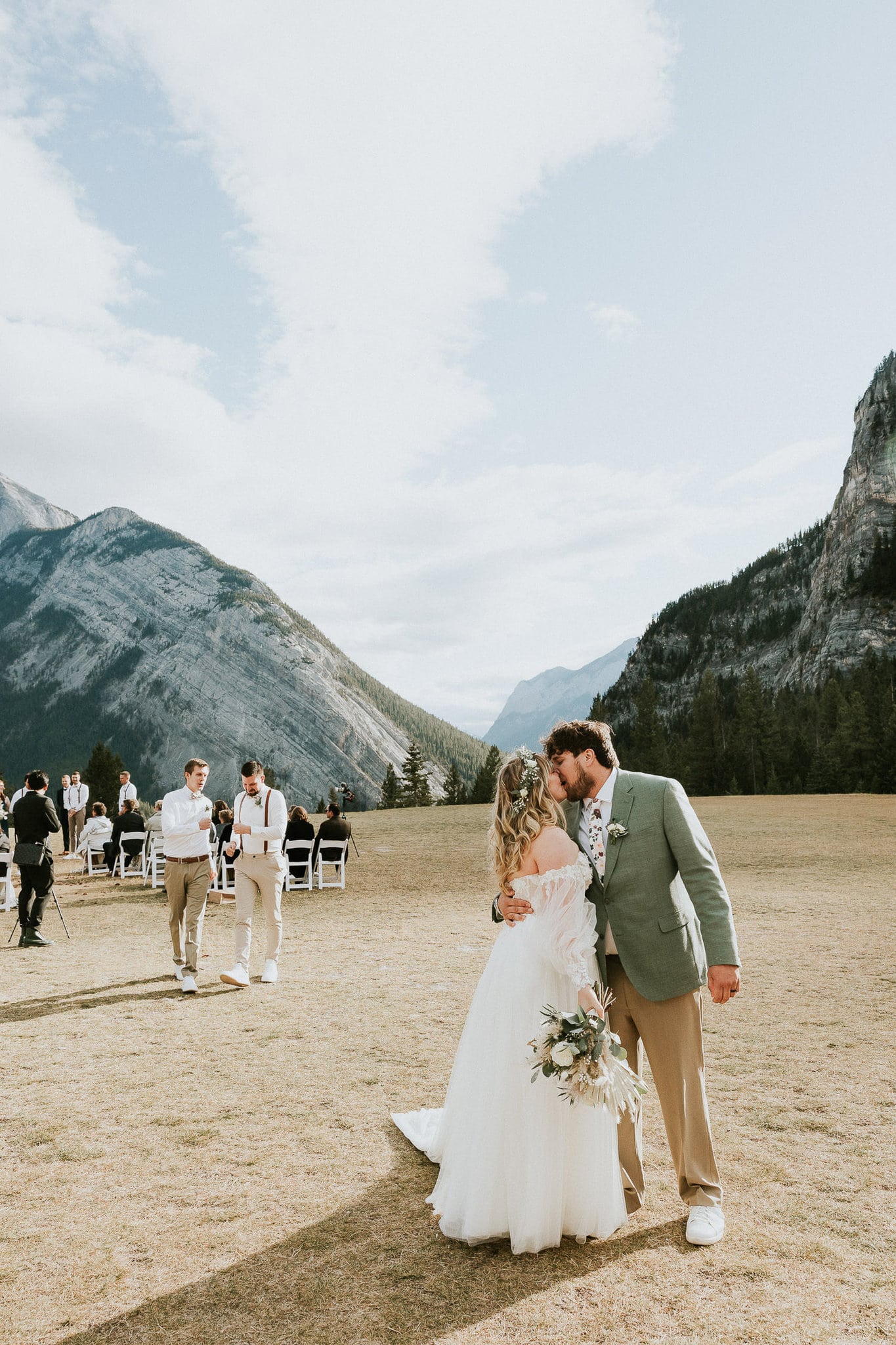 Bride and Groom walk down the aisle and stop for a kiss at their outdoor wedding in Banff